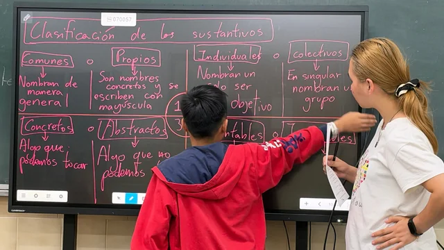 Una profesora explica gramática en la pizarra digital.