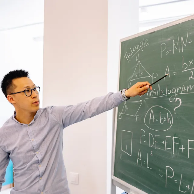 Profesor explicando geometría en una pizarra.