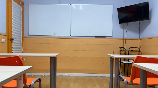 Una de las aulas, con pizarra y pantalla.